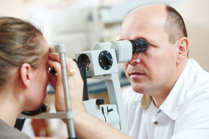 Optometrist giving an eye test to a young woman
